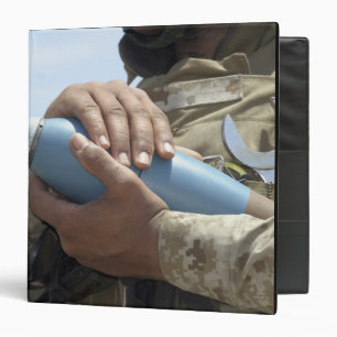 Close-up view of a soldier cradling a munition 3 ring binder