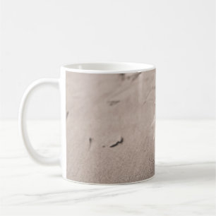 Closeup photo of white seashell on sand coffee mug