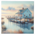 Coastal Cottage at Sunrise Marsh Ceramic Tile<br><div class="desc">This peaceful illustration captures a charming blue coastal cottage nestled beside a calm marsh, bathed in the soft light of sunrise. The artwork evokes a sense of stillness and solitude, with gently swaying reeds, a weathered dock, and mirrored reflections in quiet waters. Warm pastel tones blend seamlessly with cool blues,...</div>