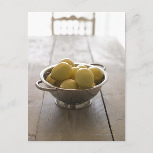 Colander with lemons on wooden table postcard