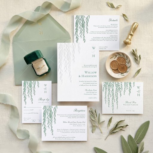 A collection of letterpressed wedding stationery with a sage green color scheme. Items like a ring and some coins are placed alongside the stationery.