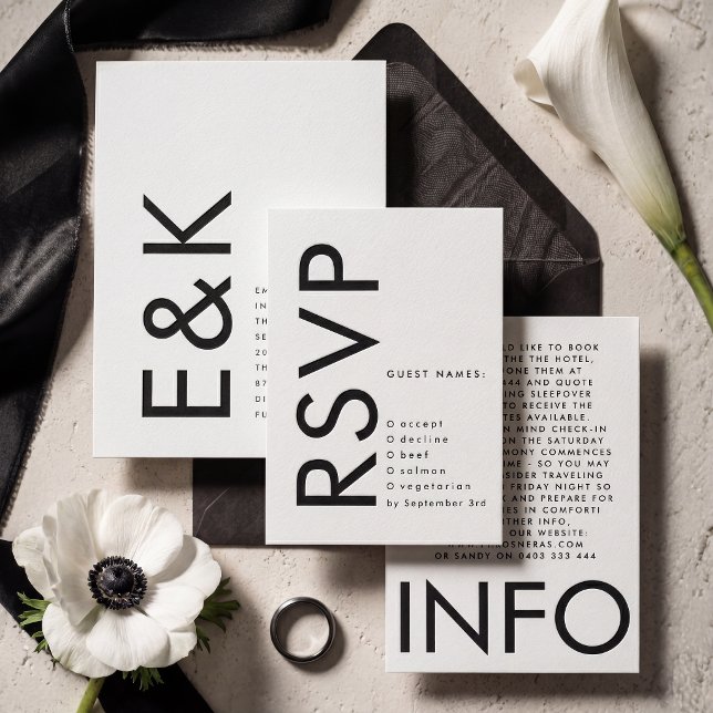 A collection of letterpressed wedding stationery with a black and white color scheme. A white flower with a black center can be seen to the left.
