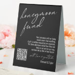 Contemporary Honeymoon Fund QR Code Black Table Tent Sign<br><div class="desc">This collection features an elegant, modern, handwritten font to create key words and phrases. In this piece, the graphic typography overlays read "honeymoon fund" in the large header area and "with love & gratitude" before your names. Use the template fields to update your personal gratitude note and names. Feel free...</div>