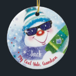 Cool Yule, Grandson, Snowman in Shades, Christmas Ceramic Ornament<br><div class="desc">A fun, snowman wearing a woolen hat and dark shades is holding up a Christmas present on the front of this (COOL YULE) Christmas ornament for Grandson. He is surrounded by tiny stars and falling snowflakes, and presents with a candy cane sitting on a bed of white snow against a...</div>
