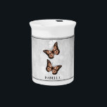 Copper Butterfly Floral Beverage Pitcher<br><div class="desc">Serve your hot or cold beverages with this unique Copper Butterfly Floral Personalized Porcelain Pitcher. Pitcher design features a pair of vibrant butterflies resting on a white floral vine against a light gray grunge background. Additional gift items available with this design as well as a variety of colors.</div>