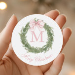 Coquette Pink Bow Monogram Wreath Christmas Classic Round Sticker<br><div class="desc">Add a charming touch to your holiday gifts with these personalized stickers featuring a delightful watercolor crest design. The festive green Christmas wreath,  adorned with a beautiful pink bow will bring a playful yet elegant feel to your holiday wrapping.</div>
