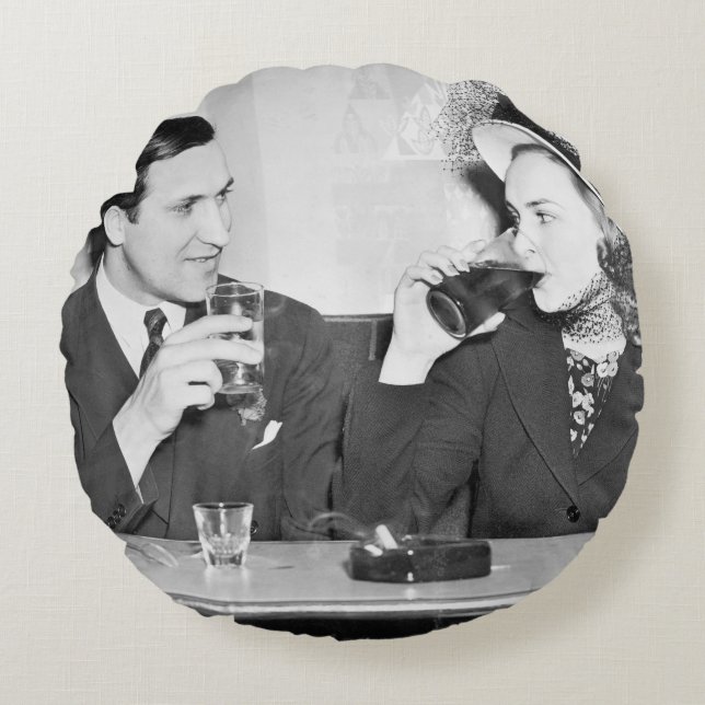Couple sitting together in a restaurant flirting w round pillow (Front)