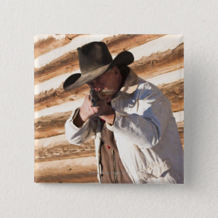 Cowboy aiming his gun, standing by an old log button