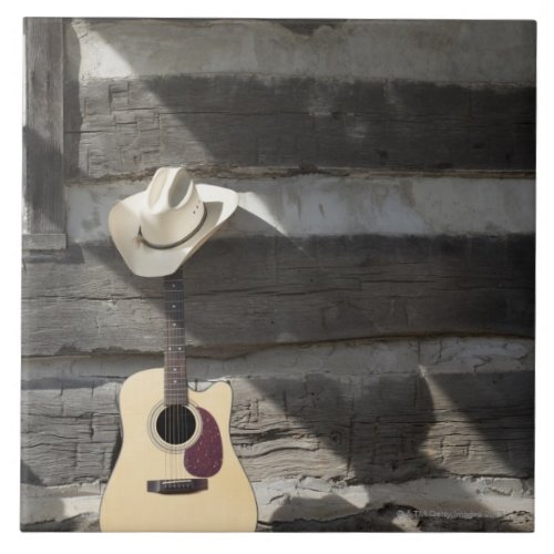 Cowboy hat on guitar leaning on log cabin tile