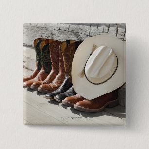 Cowboy hat on row of cowboy boots outside a log button