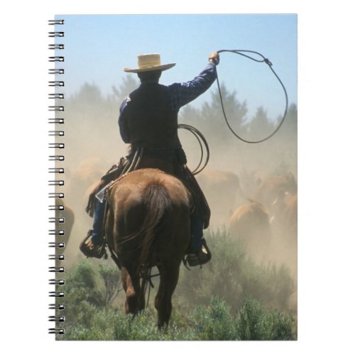 Cowboy on horse with lasso driving cattle notebook