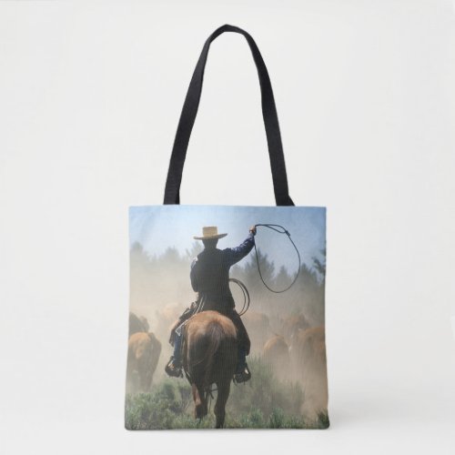 Cowboy on horse with lasso driving cattle tote bag