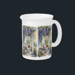Cozy Porch with Wisteria and Butterflies Beverage Pitcher<br><div class="desc">This tranquil watercolor design captures the essence of a slow, sunlit afternoon on a country porch. Cascading wisteria blooms in soft purples drape over a weathered pergola, framing a peaceful scene centered around a cozy rocking chair topped with a quilted cushion. A wide-brim straw hat rests nearby, suggesting recent company,...</div>