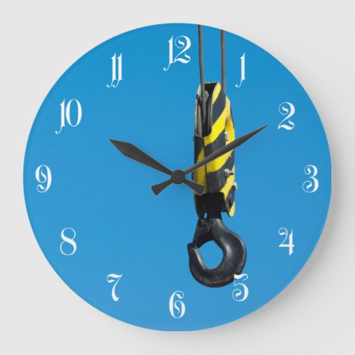 Crane hook with yellow and black stripes hanging large clock