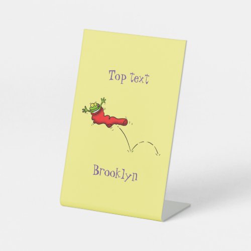 Cute frog in a red sock jumping cartoon pedestal sign