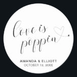 Cute Heart Popcorn Favors Modern Wedding Classic Round Sticker<br><div class="desc">Typography wedding favor stickers featuring the message, "Love Is Poppin" in black calligraphy with a heart dotting the "i's" and a swash at the end and your names and date below, over a white background. The simple and minimal layout and lots of open space give this design a modern feel...</div>