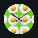 Cute pop art eggs on lime green background round clock<br><div class="desc">Cute and quirky brightly coloured design of fried eggs in Pop Art style in a pattern on a lime green background. Suitable food motif for an Easter present or just for something a bit off the wall. Featuring the bright colours of canary yellow, lime / grass green and white.</div>