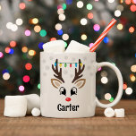 Cute Reindeer Boy Christmas Lights Custom Name Coffee Mug<br><div class="desc">Cute Christmas coffee or hot cocoa mug features an illustration of a sweet Rudolph reindeer boy face with a shiny red nose, eyelashes, and antlers. He is dressed up with a strand of colorful Christmas light bulbs and surrounded by light gray snowflakes. Personalize this festive hot chocolate mug with a...</div>