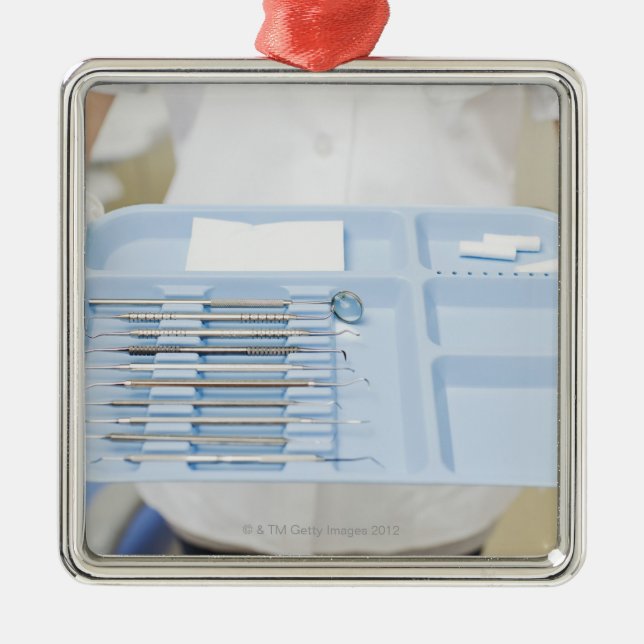 Dental hygienist  holding tray of dental metal ornament (Front)