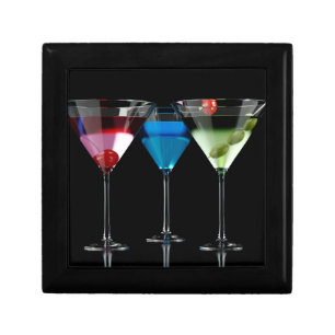 Different cocktails in martini glasses on black gift box
