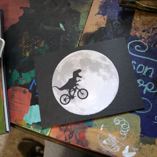 Dinosaur on a Bike In Sky With Moon Postcard