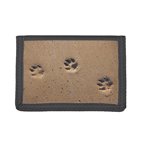 Dog paw prints on a sandy beach tri_fold wallet