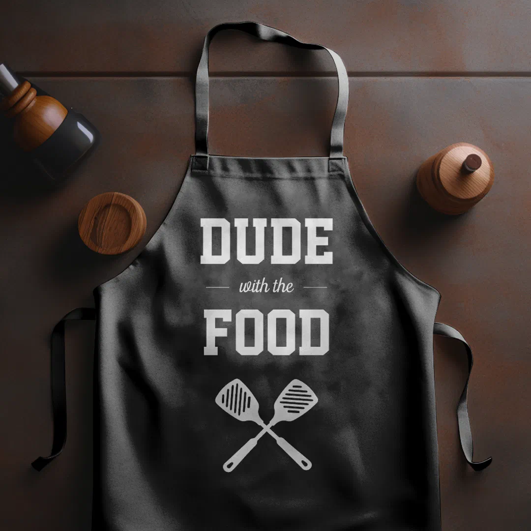 A dark brown background with a salt and pepper shaker placed above the dark gray apron with white text.