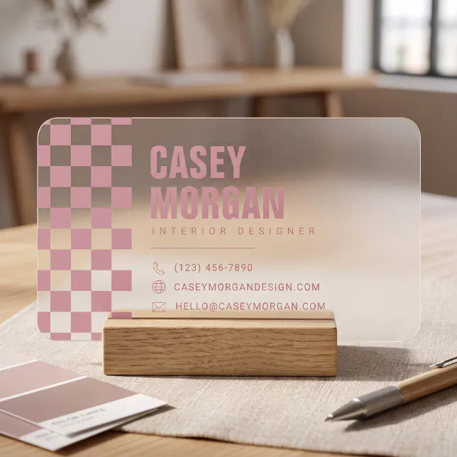A frosted business card sitting in a holder on an office table. A pen and some color samples are lying next to it.
