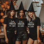 Eat Drink and Be Scary Modern Typography Halloween T-Shirt<br><div class="desc">This scary cute women's graphic Halloween t-shirt features the phrase "Eat Drink and Be Scary" in a modern white typography design with an orange jack o'lantern pumpkin accent and text that can be personalized with your names or family name.</div>