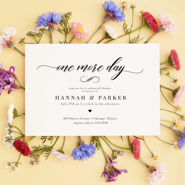 A white rehearsal dinner invitation. The invitation is lying against a bunch of wildflowers. The background is a pale yellow.