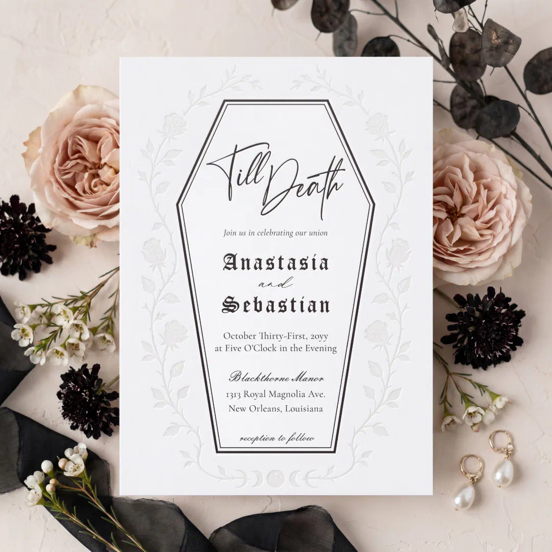 The invitation design illustrates the border of a coffin with a range of text styles on the inside. There's a transparent floral border around the the invitation. In the background there's different flowers and black leaves. In the bottom right corner there's a pair of pearl earrings.