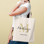 Elegant Gold Black Custom Wedding Bridesmaid Name Tote Bag<br><div class="desc">Elegant custom wedding tote bag features a personalized monogram typography design with modern calligraphy script name and serif monogram initial in rich gold and black colors. Includes custom text for a bridal party title like "BRIDESMAID" or other preferred wording.</div>