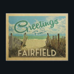 Fairfield Beach Vintage Travel Postcard<br><div class="desc">This Greetings From Fairfield vintage postcard design features a sandy beach with a beautiful turquoise ocean water and above the sea, a blue sky with billowy white clouds. In vintage travels style.</div>