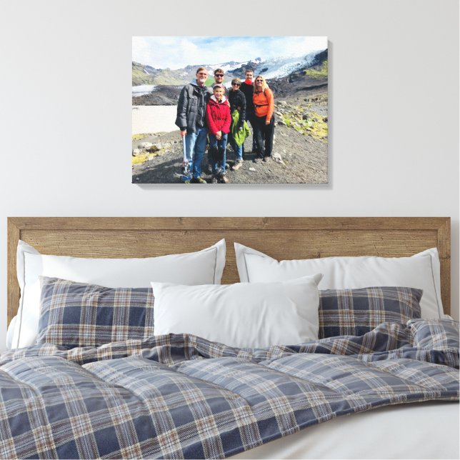 A photo canvas print displaying a family photo during a walk/hike is seen hanging above the center of a bed. 