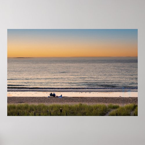 Family sitting on the beach at sunset poster