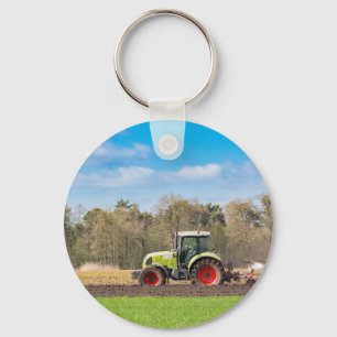 Farmer on tractor plowing sandy soil in spring keychain