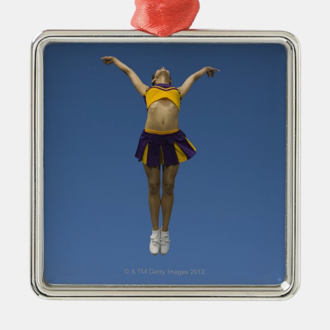 Female cheerleader jumping in air, front view metal ornament (Front)