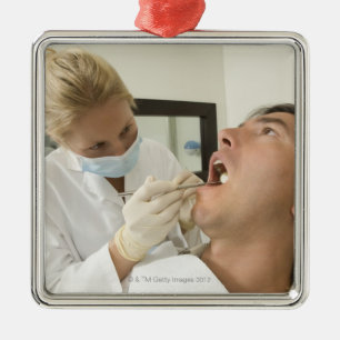 Female dentist examining man metal ornament