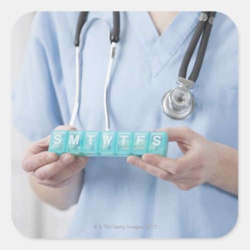 Female doctor holding pill box mid section square sticker