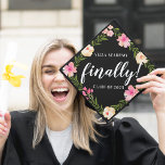 Finally | Custom School and Class Year Graduation Cap Topper<br><div class="desc">Cute personalized grad cap topper features your school and class year with "finally!" in the center,  in white brush script lettering on a black background adorned with pink watercolor flowers and green foliage.</div>