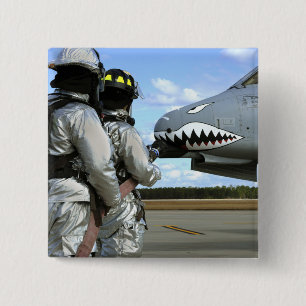 Firefighters deploy a fire hose during a drill pinback button