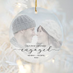 First Christmas Engaged Custom Photo Black Script Ceramic Ornament<br><div class="desc">Commemorate your engagement with this beautiful modern keepsake ornament. The black text reads "Our first Christmas engaged, " with the word "engaged" in elegant script with swashes before and after. Replace the sample image with your favorite photo, and add your names and the year. A white gradient filter helps make...</div>