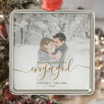 First Christmas Engaged Custom Photo Gold Script Metal Ornament<br><div class="desc">Commemorate your engagement with this beautiful modern keepsake ornament. The gold-colored text reads "Our first Christmas engaged, " with the word "engaged" in elegant faux foil handwriting script with flourishes before and after. Replace the sample image with your favorite photo, and add your names and the year. A white gradient...</div>