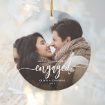 First Christmas Engaged Custom Photo White Script Ceramic Ornament<br><div class="desc">Commemorate your engagement with this beautiful modern keepsake ornament. The white text reads "Our first Christmas engaged, " with the word "engaged" in elegant calligraphy script with decorative swashes before and after. Replace the sample image with your favorite photo, and add your names and the year. A black gradient filter...</div>