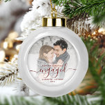 First Christmas Engaged Photo Burgundy Script Ceramic Ball Christmas Ornament<br><div class="desc">Commemorate your engagement with this beautiful modern keepsake ornament. The burgundy red text reads "Our first Christmas engaged, " with the word "engaged" in elegant handwriting script with flourishes before and after. Replace the sample image with your favorite photo, and add your names and the year. A white gradient filter...</div>