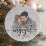 First Christmas Engaged Photo Gray Script Ceramic Ornament<br><div class="desc">Commemorate your engagement with this beautiful modern keepsake ornament. The charcoal gray text reads "Our first Christmas engaged, " with the word "engaged" in bold handwriting script with flourishes before and after. Replace the sample image with your favorite photo, and add your names and the year. A white gradient filter...</div>