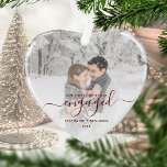 First Christmas Engaged Photo Red Script Heart Ornament<br><div class="desc">Commemorate your engagement with this beautiful heart-shaped keepsake ornament. The dark red text reads "Our first Christmas engaged, " with the word "engaged" in elegant handwriting script with flourishes before and after. Replace the sample image with your favorite photo, and add your names and the year. A white gradient filter...</div>