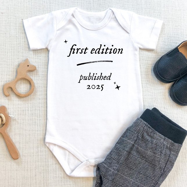 First Edition Book Published 2025 Baby bodysuit (First edition baby bodysuit with personalized birth year. Shown on beige table with baby pants. book)