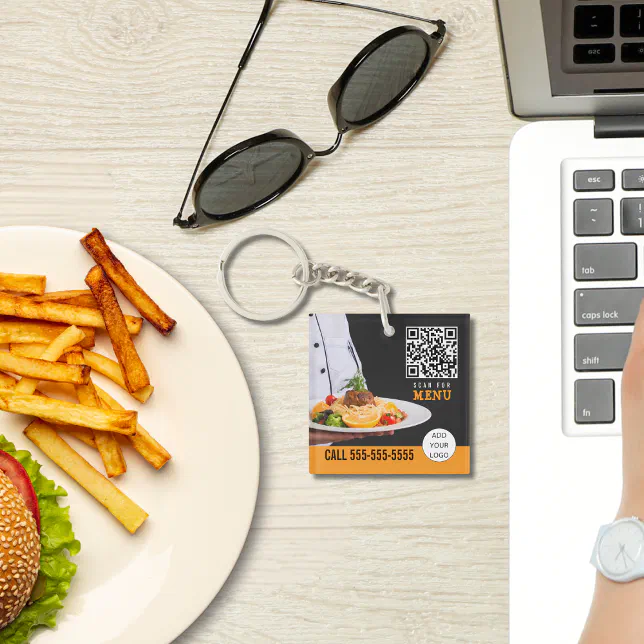 A keychain is featured in the middle with a plate of fries and a burger, sunglasses, and a laptop around it.