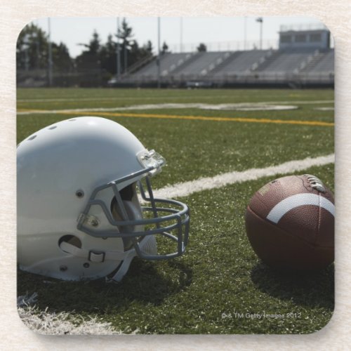 Football and football helmet on football field coaster